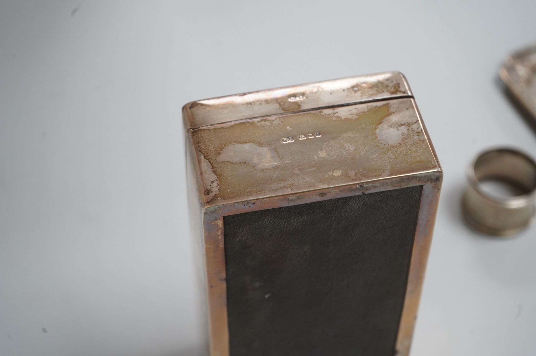 A George VI silver mounted rectangular cigarette box, Atkin Brothers, London, 1944, 17.3cm, together with a small silver dish, William Comyns & Sons Ltd, London, 1945, an Edwardian silver napkin ring and a George III sil